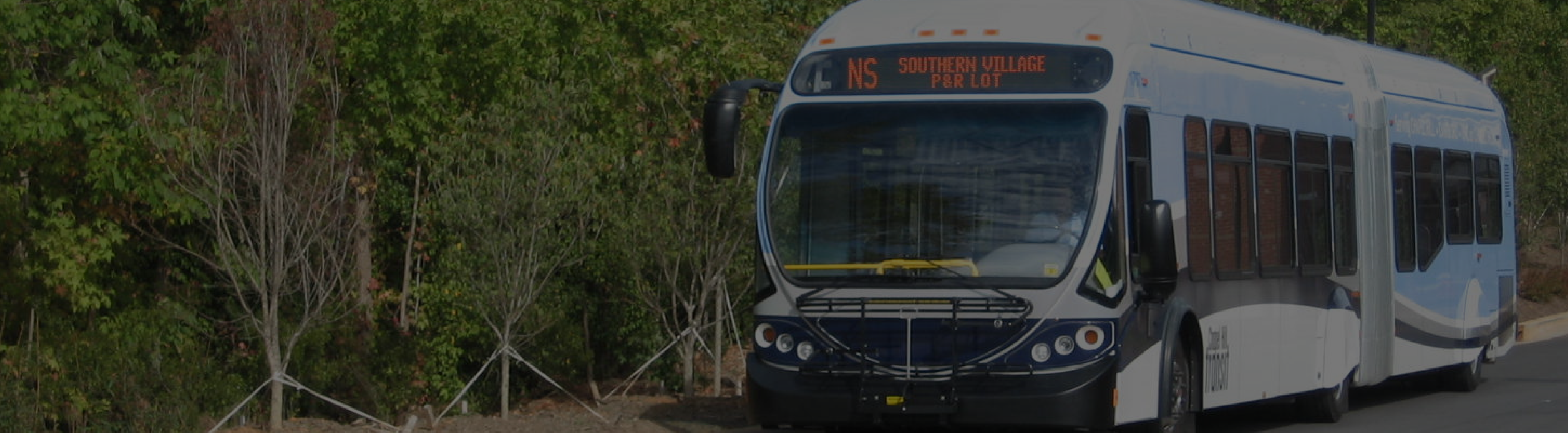 An articulated Chapel Hill Transit bus parked on the side of the road.